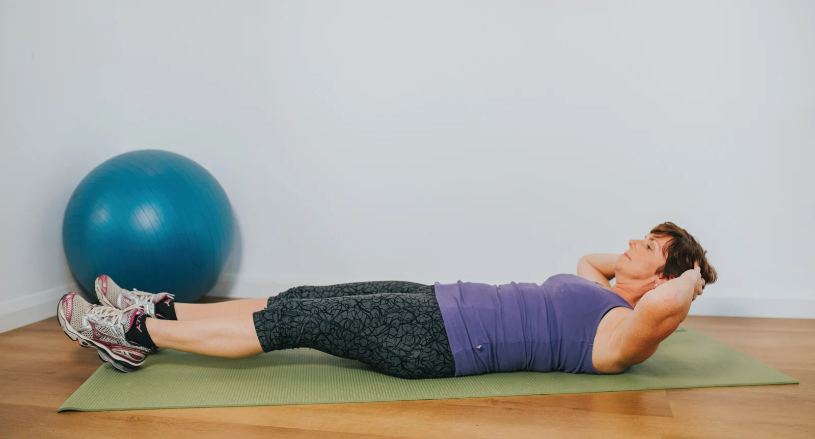 a person lying on a yoga mat with a blue ball